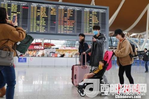 旅客帶著孩子前往辦票柜臺辦理登機(jī)手續(xù)。　殷立勤 攝