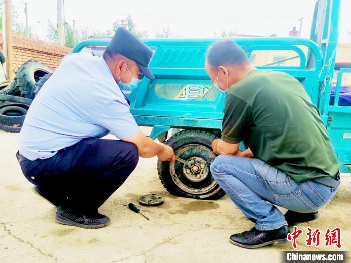 賽旦與民警共同維修三輪摩托車(chē)。　依力哈木江 攝